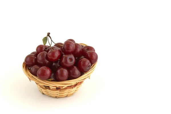 Свежие красные вишни в плетеной корзине изолированы на белом фоне — стоковое фото