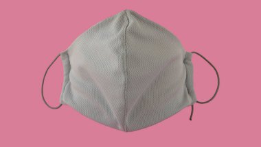 Pembe arka planda tekrar kullanılabilir tıbbi maske. Coronavirus COVID-19 salgını. Korona virüsüne karşı korunmak için antiviral tıbbi maske. Cerrahi koruyucu maske. Tıbbi solunum bandajı yüzü.