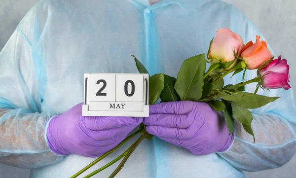 doctor with a bouquet of flowers in his hands. medical worker in surgical gown and medical gloves.