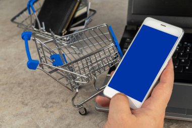Adam cep telefonundan ürün sipariş ediyor. Alışveriş arabası. Seçici odaklanma. çevrimiçi alışveriş.