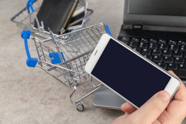 Adam cep telefonundan ürün sipariş ediyor. Alışveriş arabası. Seçici odaklanma. çevrimiçi alışveriş.