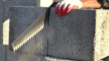 Köpük beton bir bloğu testereyle kesmek. Bir ev inşa etme fikri