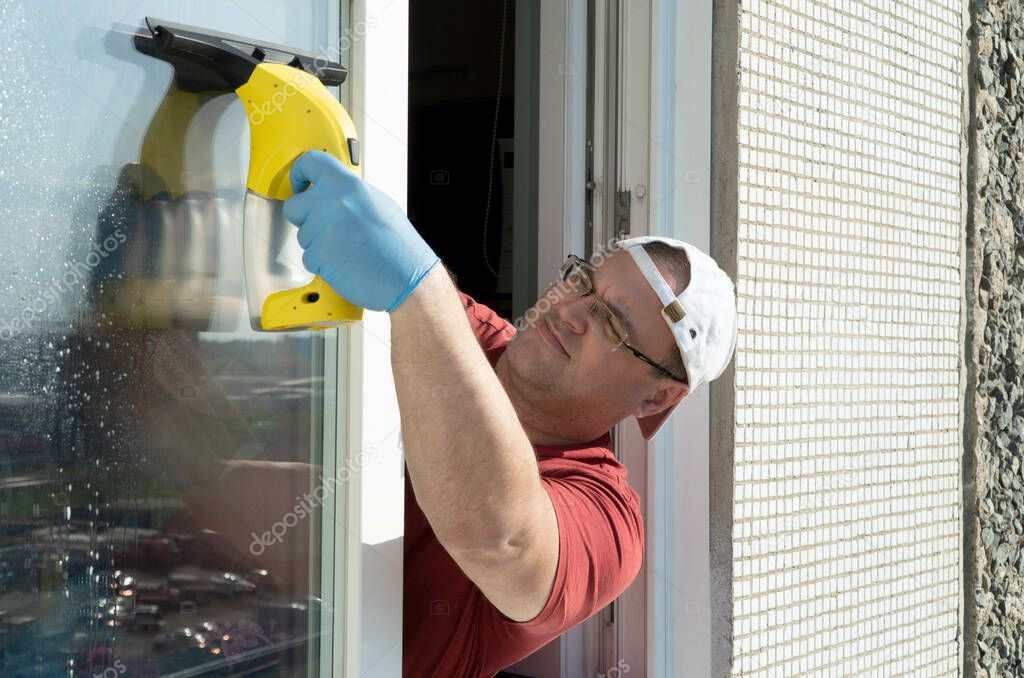 man cleans glass window openings. service cleaning of apartments. regular cleaning and sanitary treatment of surfaces in offices and homes
