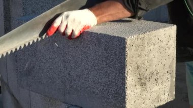 Köpük beton bir bloğu testereyle kesmek. Bloklar doğal maddelerden yapılmış ve çevre dostu. Kendi evini inşa etme kavramı
