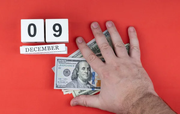 A személy keze a bankjegyeken van. naptár és pénztárca pénzzel. Kézzel készített fa kocka dátum hónap és nap. — Stock Fotó