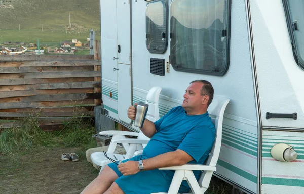 Mann entspannt sich mit Reiseanhänger. Person im Urlaub mit einem Becher in der Hand. — Stockfoto