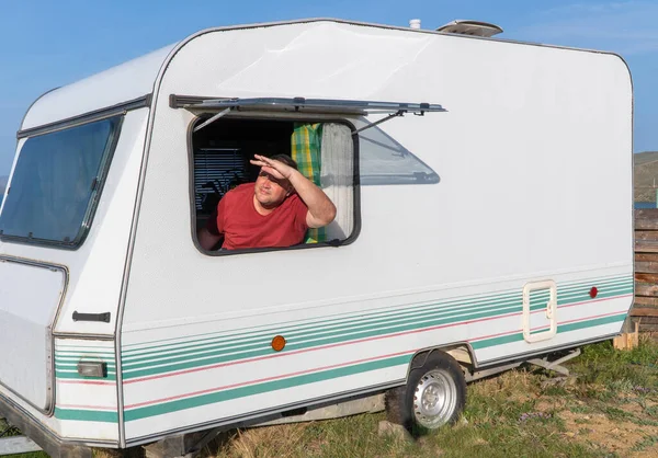 man is relaxing with a travel trailer. caravan trailer of large size, equipped with all necessary household appliances to ensure the comfort of the traveler