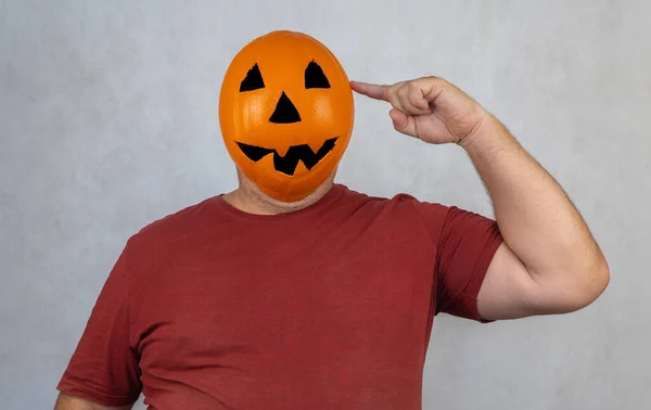 man in a Halloween mask on a white background. person with orange pumpkin evil mask.