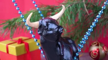 2021 yılının sembolü olarak Noel boğası. Kırmızı arka planda şenlikli Noel süsleri. Noel ağacını süslemek. Doğu takvimindeki boğa yılı. Mutlu xmas