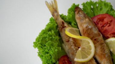 Lezzetli kızarmış balık, domates ve limon. yeşil marul yaprakları üzerinde tabak