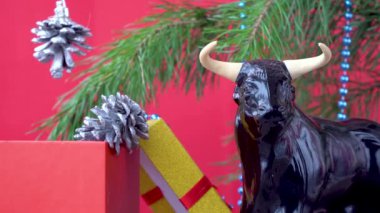 2021 yılının sembolü olarak Noel boğası. Kırmızı arka planda şenlikli Noel süsleri. Xmas boncukları. Noel ağacını süslemek. Doğu takviminde boğanın yılı. 