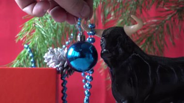 2021 yılının sembolü olarak Noel boğası. Kırmızı arka planda şenlikli Noel süsleri. Xmas boncukları. Noel ağacını süslemek. Doğu takviminde boğanın yılı. 