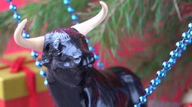 Noel boğası. 2021 yılının sembolü olarak boğa. Kırmızı arka planda şenlikli Noel süsleri. Doğu takvimindeki boğa yılı. xmas boncukları
