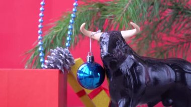 2021 yılının sembolü olarak Noel boğası. Kırmızı arka planda şenlikli Noel süsleri. Xmas boncukları. Noel ağacını süslemek. Doğu takviminde boğanın yılı. 
