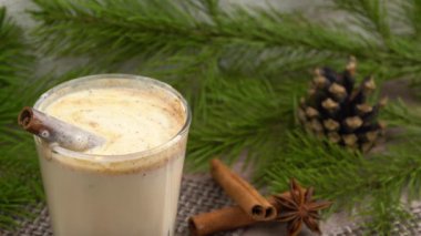 Geleneksel bayram içkisi. Rendelenmiş hindistan cevizi ve tarçınlı Noel kokteyli. Külahlı bir ladin dalının arka planı. Seçici odak.