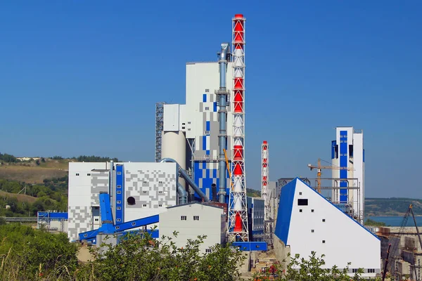 Nehir kıyısında bir çimento fabrikası inşaatı. Yeni cepheler ve İnşaat ekipmanları. Arka planda nehir akar.
