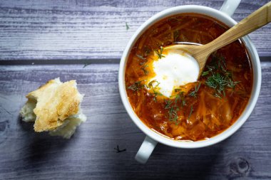 Tahta kaşıkla beyaz bir bardakta çorba. Th arka planda