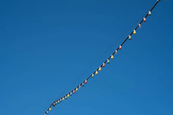 Décorations festives. Lampes sur le fil pour décorer la rue. Photo prise contre le ciel bleu . — Photo