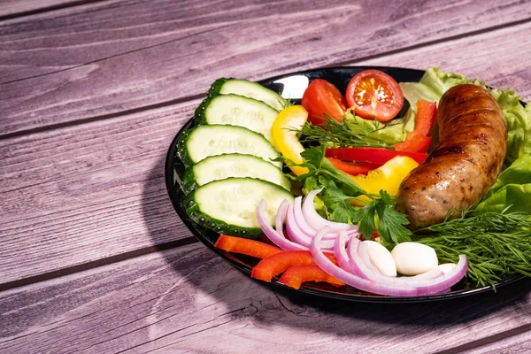 Sebze ve panoları bir arka plan ile siyah bir tabak üzerinde Güzel ızgara sosis.