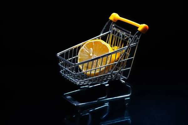 Close-up de carrinhos de compras sobre fundo preto Trolley, Conceito de venda Isolado sobre fundo preto em um carrinho encontra-se um limão . — Fotografia de Stock