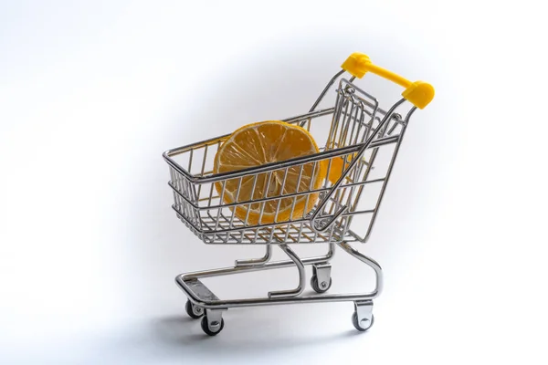 Close-up de carrinhos de compras no fundo branco. Trolley e limon, conceito de venda. Isolado sobre fundo branco em um carrinho encontra-se um citrino amarelo . — Fotografia de Stock