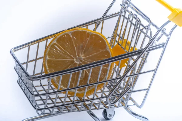 Nahaufnahme von Einkaufswagen auf weißem Hintergrund. Trolley und Limone, Verkaufskonzept. isoliert über weißem Hintergrund in einem Einkaufswagen liegt eine gelbe Zitrusfrucht. — Stockfoto
