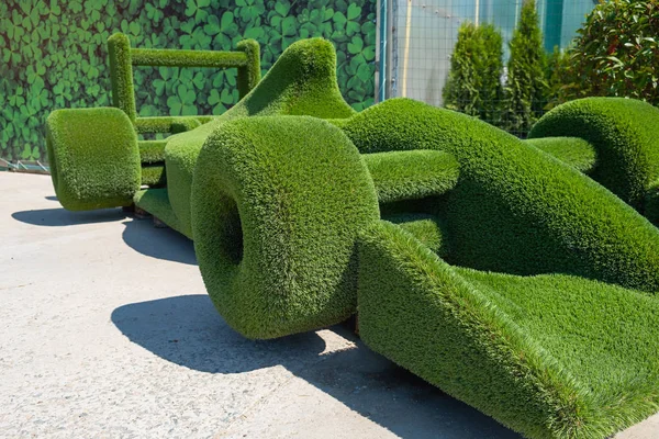 The figure of a sports car covered with grass. Figure  made of green lawn grass in the park, free space. Green grass covered topiary , landscape design. — Stock Photo, Image