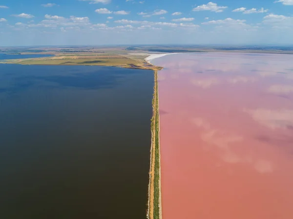 Růžové jezero Sasyk Sivash. Cesta vede do dálky a odděluje pobřeží. Převzata z dronu. Stock Obrázky