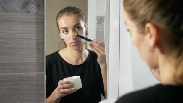 Mädchen mit Akne im Gesicht ist ein Badezimmer neben dem Spiegel