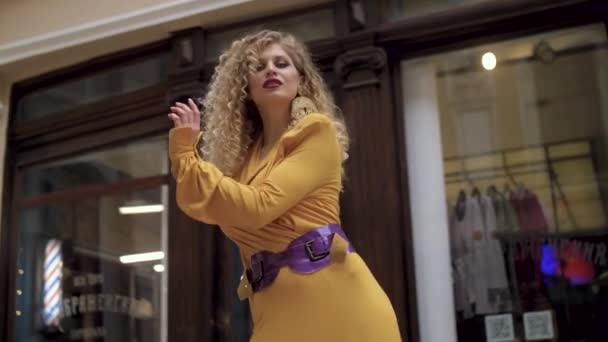 Lány ruha sárga és piros kabátot pózol a kamera a folyosón — Stock videók