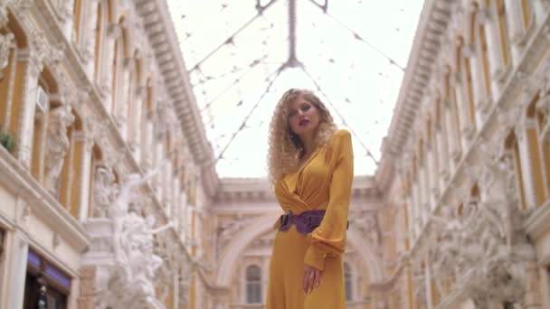 Kız bir sarı elbise ve kırmızı ceket pasajda kamera için poz — Stok video