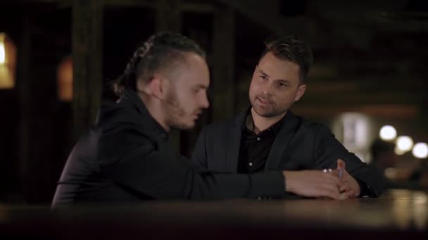 Два чоловіки в костюмах п'ють віскі в барі — стокове відео