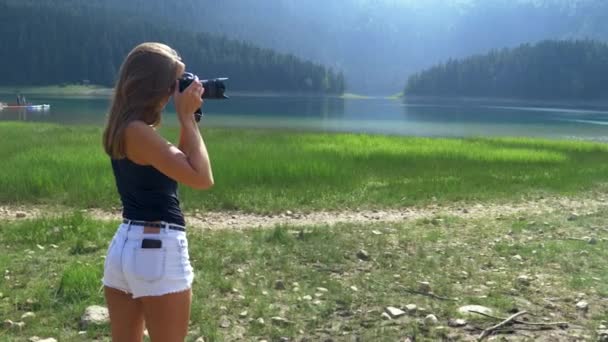 Menina tira uma foto fica contra o fundo da paisagem . — Vídeo de Stock