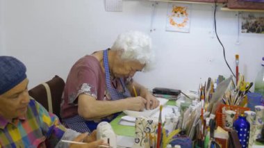 Beyaz kadın çömlekçi çömlekçi dükkanında bir sürahi boyama