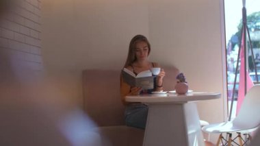 bir kafede kız bir kitap ile yapraklama