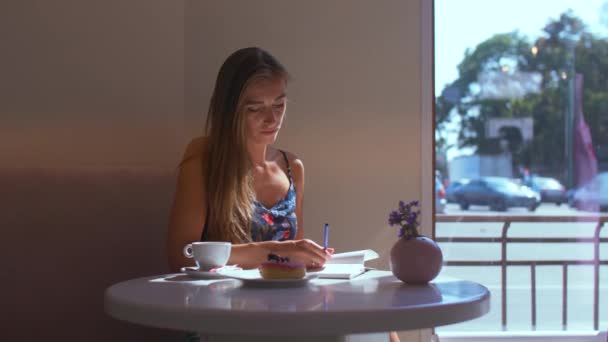 Κορίτσι σε ένα καφέ που ξεφυταίζει ένα βιβλίο — Αρχείο Βίντεο
