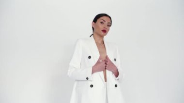 Beyaz ceketli kız stüdyoda poz veriyor.