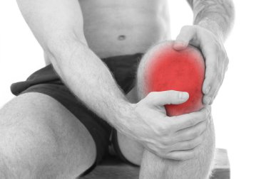 Beyaz zemin üzerinde diz ağrısı olan adam