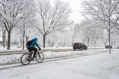 Montreal, CA - 14 Mart 2018: Kar fırtınası sırasında bir adam karlı bir sokakta bisiklet sürüyor