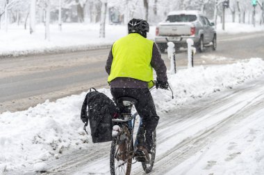 Montreal, CA - 14 Mart 2018: Kar fırtınası sırasında bir adam karlı bir sokakta bisiklet sürüyor
