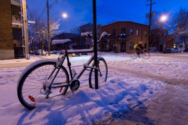 Montreal, CA - 17 Şubat 2018: Kar fırtınası sırasında arka planda bisiklet süren biri olarak bisiklet