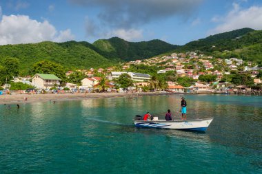 Petit Anse, Martinique, 18 Ağustos 2019: Kayıktaki balıkçılar ve körfez ve tepelerin genel manzarası.