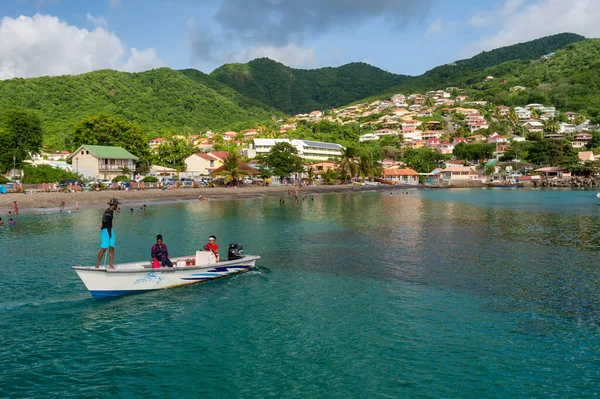 Petit Anse, Martinique, 18 Ağustos 2019: Kayıktaki balıkçılar ve körfez ve tepelerin genel manzarası.