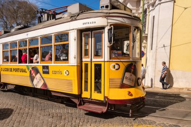 Lizbon, Portekiz - 8 Mart 2020: Alfama bölgesindeki ünlü sarı tramvaya binen turistler