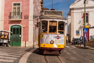 Lizbon, Portekiz - 8 Mart 2020: Alfama bölgesindeki ünlü sarı tramvaya binen turistler
