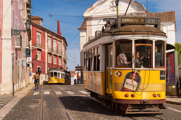 Лиссабон, Португалия - 8 марта 2020 года: Туристы на знаменитом желтом трамвае 28 в районе Алфама
