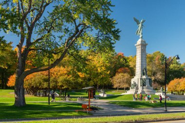 Montreal, Kanada - 14 Ekim 2018: İnsanlar George-Etienne Cartier Anıtı 'nın yanında dururken, sonbahar renkleriyle Mont-Royal yeşillikleri patlıyor.