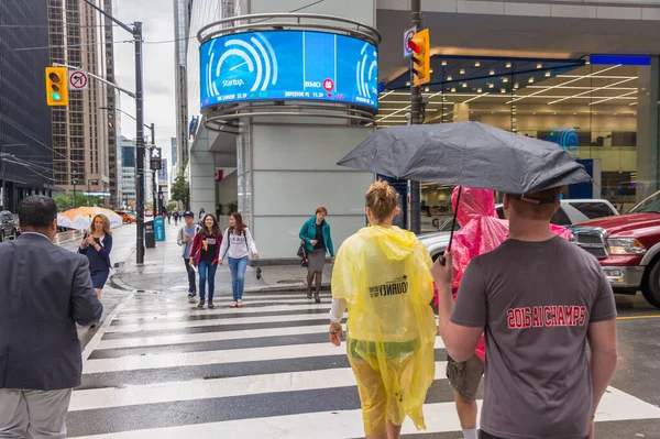 Toronto, Canada - 26 June 2017: Crowd of people with umbrellas and rain ponchos on a rainy day