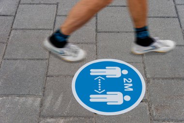 Sign printed on ground informing people to keep a 2 meter distance from each other during Covid-19 pandemic. clipart