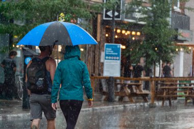 Montreal, CA - 30 Temmuz 2020: Mont-Royal Caddesi 'ndeki insanlar yağmur ve fırtına sırasında şemsiye tutuyorlar